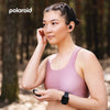 Woman in a forest wearing a pink sports bra and black PA86 Polaroid Fit Active Watch, with Polaroid branding.