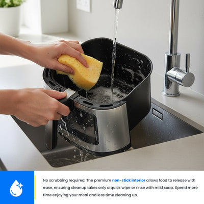 Person cleaning an air fryer with a sponge in a kitchen sink.