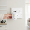 Person holding a ultrasonic pest device against a wall socket
