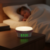 Polaroid light and charging device on a nightstand with a person sleeping in the background